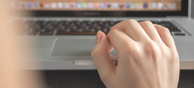 A close-up image of a hand typing on a laptop keyboard with the reflection of the US flag on the screen, symbolizing the process of applying for a government job online. The lighting is soft and focused, highlighting the concentration on the task.