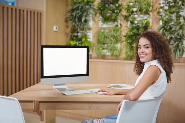 A young woman sitting at a desk, looking happily at her computer screen with a surprised expression, indicating she just received news about a scholarship. The room is well-lit and suggests a home study environment.