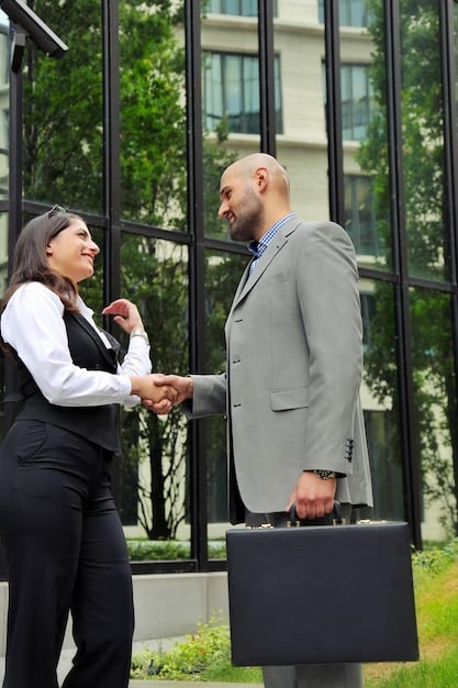 A student in a business suit shakes hands with a professional in an office. The scene conveys a mentoring relationship, with the professional providing guidance and the student looking eager and engaged.